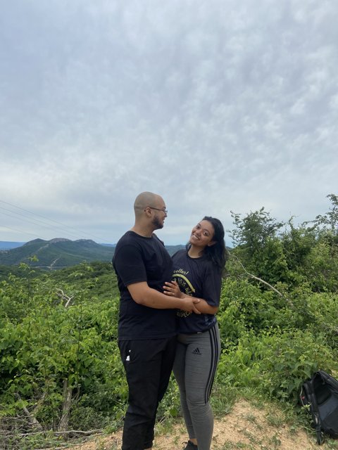 Ana e Arthur juntos em uma paisagem verde.